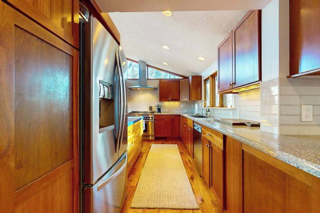 A modern kitchen with wooden cabinets, stainless steel appliances, and a tiled backsplash.