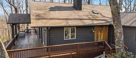 Une cabane avec une terrasse, une cheminée et une fenêtre.