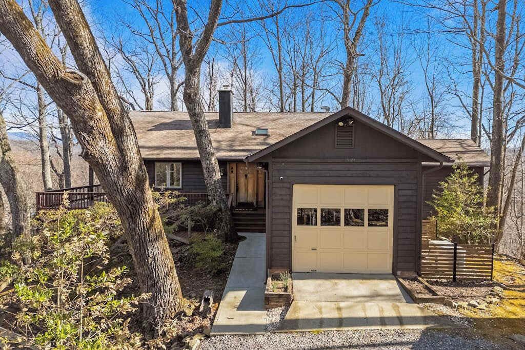 Une cabane avec un garage, entourée d’arbres.