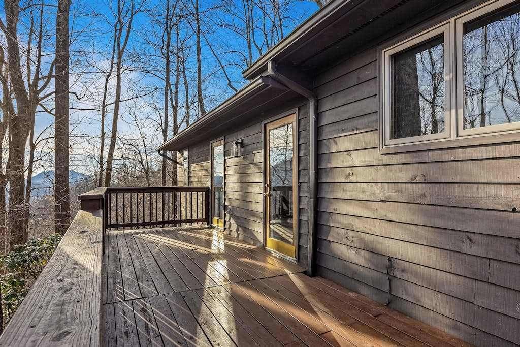 Una cabaña de madera con terraza, ventanas amplias y una puerta que da a un espacio cubierto.