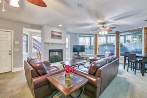 A living room with a fireplace, leather sofas, a coffee table with flowers, and a television. - Lower level unit in duplex with AC, fireplace, washer & dryer, community pool (Lake Junaluska)