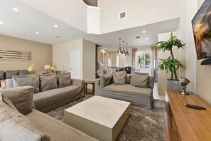 A spacious living area with a large sofa set, a coffee table, and a TV on a wooden stand. - Upscale 3BR suites, Patio with BBQ & Jacuzzi (Four Corners)