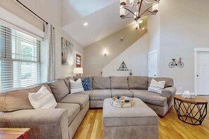 Ein Wohnzimmer mit einer Eckcouch, einem Couchtisch und einer Treppe, die zu einer weiteren Ebene führt.