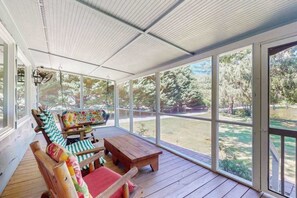Eine überdachte Veranda mit Holzboden, einer Bank und einem Schaukelstuhl.