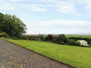 A rural landscape with a gravel path, green grass, and various shrubs. - Burnside Bothy (Girvan)