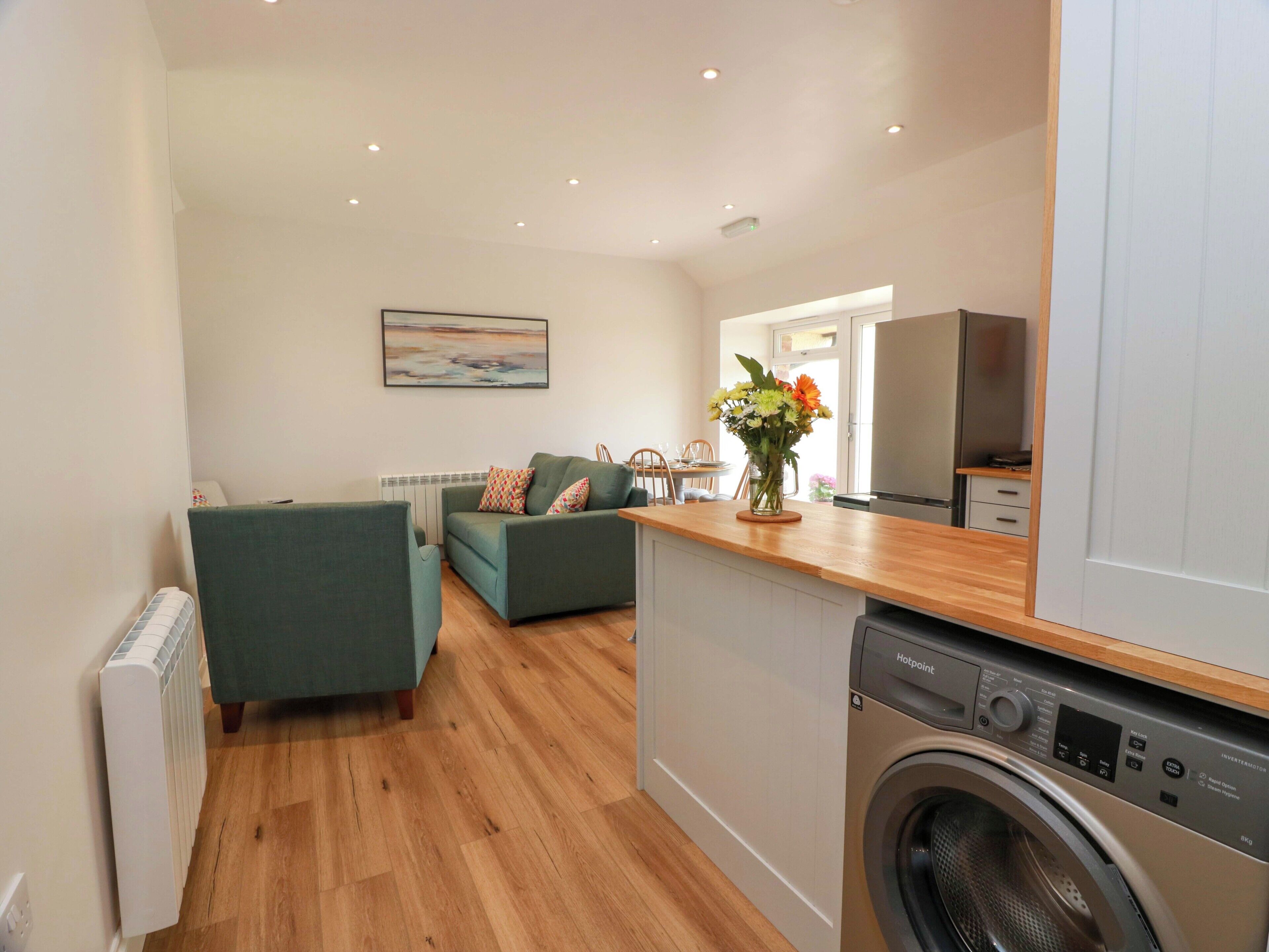 A compact living space with a sofa, a small table, a washing machine, and a radiator.
