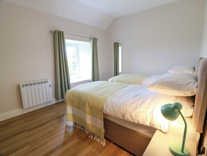 Un dormitorio con cama, radiador, ventana con cortinas y lámpara.