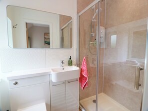 Un baño moderno con un lavabo blanco, cabina de ducha con mampara de cristal y un espejo grande.