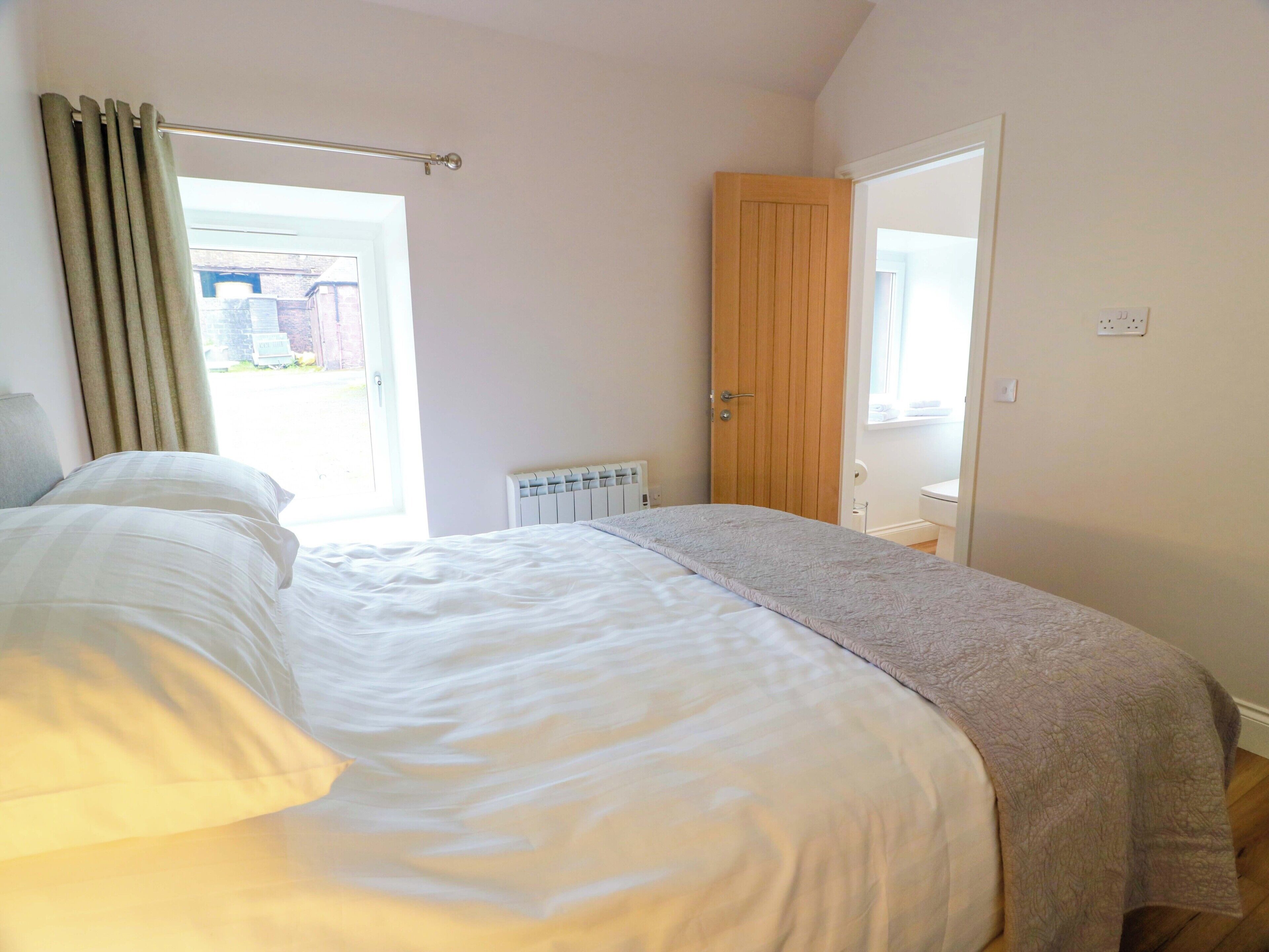 A bedroom with a bed, a radiator, a wooden door, and a window.