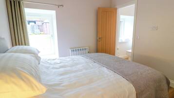 A bedroom with a bed, a radiator, a wooden door, and a window.