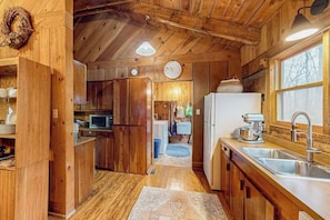 Ein Holzblock-Interieur mit Küche, Holzwänden, Deckenventilator und Fenster.