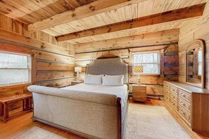 Ein Schlafzimmer in einer Blockhütte mit Bett, Kommode und Fenster.