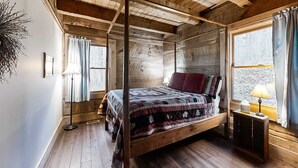 Une chambre à coucher dans une cabane en bois, avec un lit à baldaquin, une fenêtre avec des rideaux et une lampe de sol.