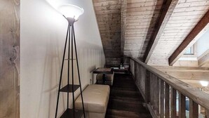 Un intérieur en bois avec un plafond en pente, un lampadaire, un banc et une petite table.