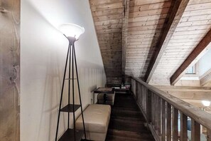 Et trægulv og interiør med skråvæg, gulvlampe, bænk og et lille bord.