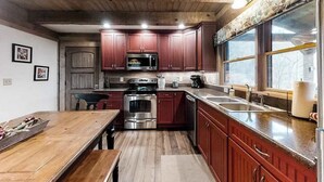 Une cuisine avec des meubles en bois, des appareils électroménagers en acier inoxydable et une grande fenêtre.