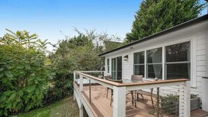 Une maison dotée d’une terrasse, d’un coin repas et d’une fenêtre donnant sur un jardin.