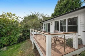 Ein Haus mit einer Terrasse, einem Essbereich und einem Fenster mit Blick auf einen Garten.
