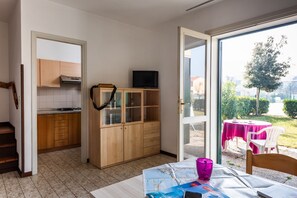 A kitchen with wooden cabinets, a television on a cabinet, and a dining area with a table and chairs. - Nice House With Garden and Pool in Bibione (San Michele al Tagliamento)