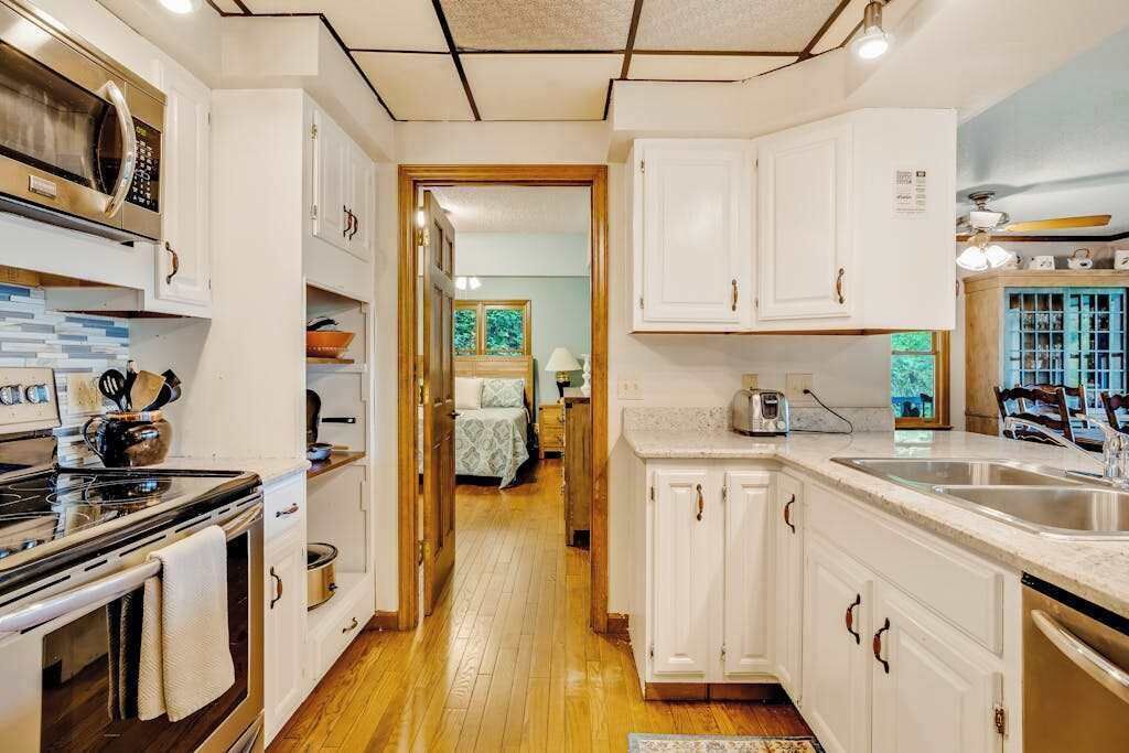 A kitchen with white cabinets, a stove, and a sink.