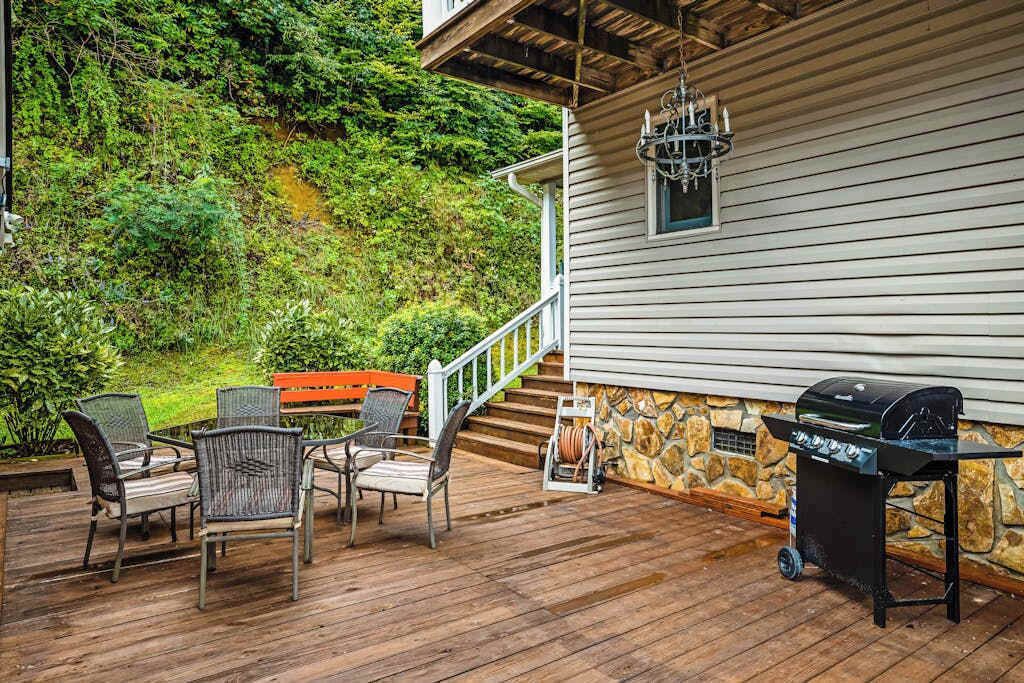 A covered outdoor patio with a stone wall, a grill, and wicker chairs.