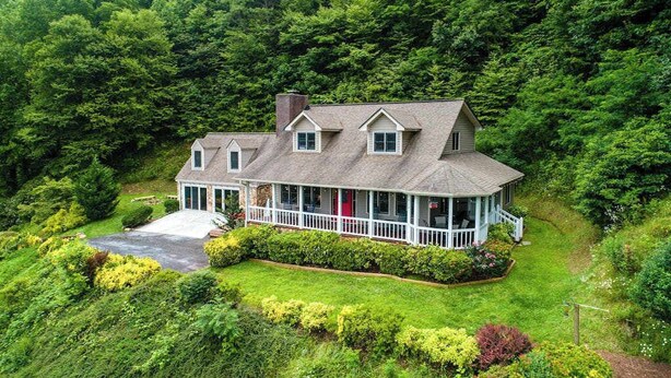 A large house with a porch, surrounded by dense forest. - Angel View (Cullowhee)