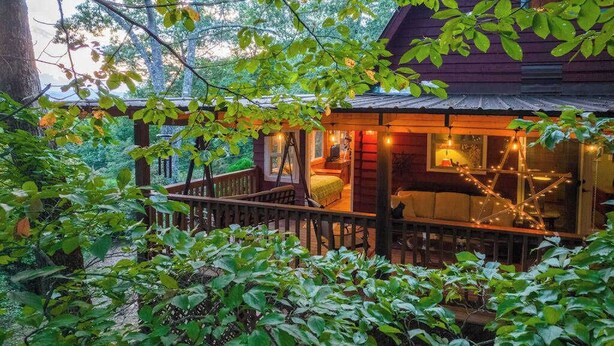 Uma cabana com varanda, cama e luzes de festa.