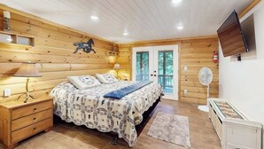 Un dormitorio con paneles de madera, una cama, lámparas de noche, un televisor y un ventilador.