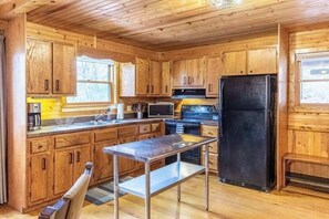Ein Interieur einer Holzhütte mit Küchenzeile, einschließlich Schränken, einem Kühlschrank, einer Mikrowelle und einem Herd.