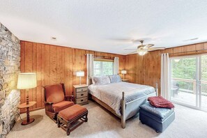 Un dormitorio con cama, una silla, una mesa y una ventana.