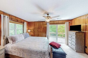 Ein Schlafzimmer mit Bett, Deckenventilator, Fernseher, Kommode und Fenster.