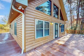 A log cabin with a deck, large windows, and a chimney. - Mountain Hideaway (Almond)