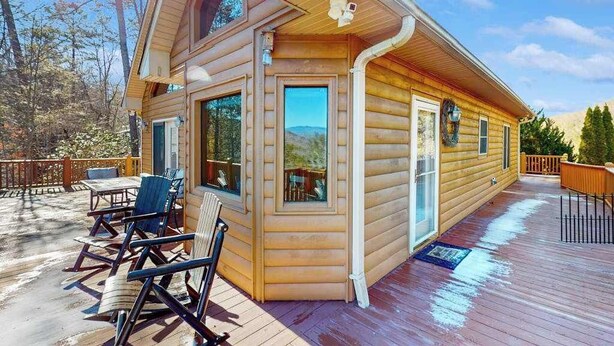 Eine Blockhütte mit einer Terrasse, Sitzgelegenheiten im Freien und Bergblick.