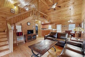 A wooden cabin interior with a living room, kitchen, and staircase. - The Orr House (Sylva)