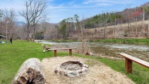 Ein Campingplatz mit Feuerstelle, Bänken und einem Fluss.