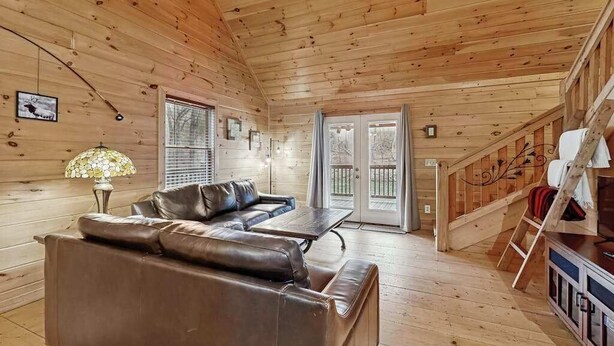 Ein Holzblockhaus-Innenraum mit Ledersofa, Tisch und Treppe.