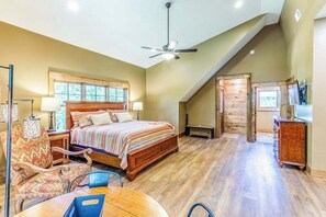Ein Schlafzimmer mit einem Bett, einem Deckenventilator, einem Fenster, einem Schreibtisch und einem Stuhl.