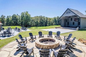 Eine Terrasse mit Adirondack-Stühlen, einer Steinkaminfeuerstelle und einem Gebäude im Hintergrund mit der Aufschrift 'Chimney House'.