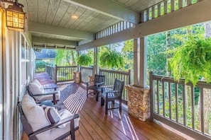A covered porch with wooden flooring, cushioned seating, and stone accents. - Carolina Cottage (Highlands)