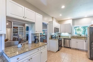 A modern kitchen with white cabinets, granite countertops, stainless steel appliances, and a window with a view. - Carolina Cottage (Highlands)