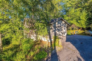 A small building with a sloped roof, surrounded by dense greenery and trees. - Carolina Cottage (Highlands)