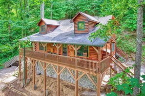 Eine Holzhütte mit Balkon, umgeben von dichtem Wald.
