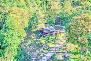Eine abgelegene Hütte, umgeben von dichtem Wald, mit einem Feldweg davor.