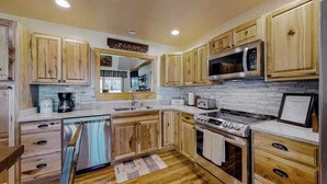 Una cocina con armarios de madera, un refrigerador de acero inoxidable, un microondas, una estufa y un lavavajillas.