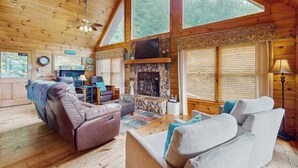 Een houten cabin met een stenen openhaard, leren banken en grote ramen.