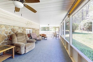 Eine überdachte Veranda mit Steinmauern, einem Deckenventilator und Blick ins Freie.