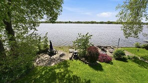 Une terrasse au bord du lac, aménagée avec du mobilier d’extérieur, un vélo et une table de pique-nique.