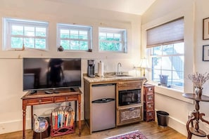 A compact kitchen with a built-in TV, a refrigerator, a microwave, and a sink. There are three windows providing natural light. - Fabulous escape with firepit, stylish interior & central AC - near hiking (Waynesville)