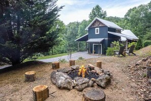 Une cabane à deux étages avec un porche, entourée d’une forêt.