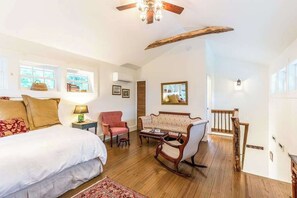 A bedroom with a bed, a rocking chair, a sofa, a small table, and a staircase. - Fabulous escape with firepit, stylish interior & central AC - near hiking (Waynesville)